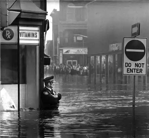 Police Officer Guarding A Pharmacy During A Flood